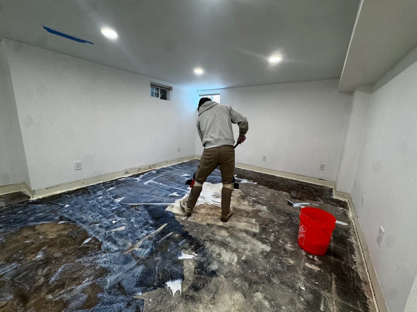 Urban Edge team member scraping a subfloor before new flooring installation